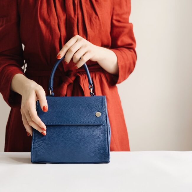 woman holding blue leather handbag