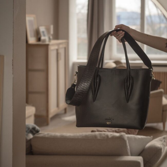 a woman holding a black purse in front of a mirror